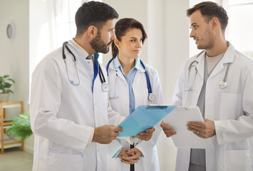Diverse medical team of doctors standing together talking, happy young practitioner woman, men in medic uniform coats posing for corporate portrait, physician specialists medical meeting to share
