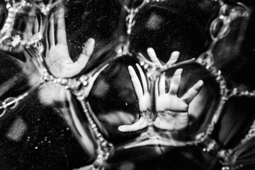 Abstract image of hands distorted and reaching through bubbles, representing mental health problems, isolation.