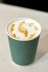 Coffee with beautiful latte art in a takeaway cup in a cozy cafe setting