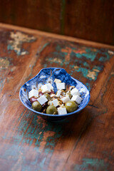 Green and kalamata olives and feta cheese on rustic wooden background. Soft focus.	