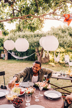 Smiling man eating fruit in back yard at party