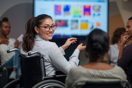 Young designer in sleek wheelchair presents vibrant visuals to engaged diverse creative team