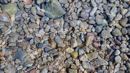 Colorful smooth pebbles under clear water at the seashore