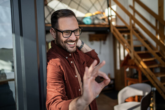 Happy man in glasses making ok gesture indoors