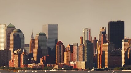 Aerial view of a city skyline during sunset, with skyscrapers and water bodies visible. The sky is clear with a gradient of colors.