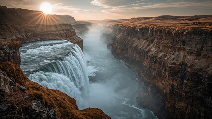 Spectacular view of a waterfall at sunset, with mist rising from the cascading water and rugged canyon walls.