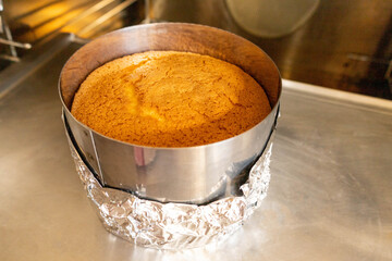 cake sits on crumpled aluminum sheet cooling, dessert rests as it cools atop textured aluminum surface