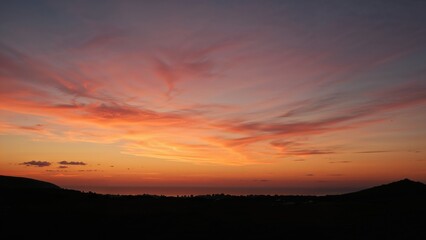 Sunset sky with vibrant orange, pink, and purple hues over a silhouetted landscape.