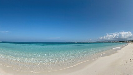 Tropical beach with clear blue water and white sand under a bright sky. Coastal scenery with calm waves and distant horizon.