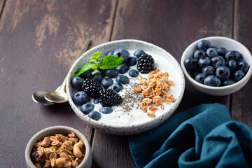 Greek yogurt bowl with berries, granola on a wooden table. Healthy food