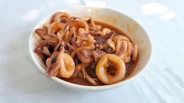 A bowl of squid in sweet and sour sauce. Seafood typical of Asian cuisine. Footage.