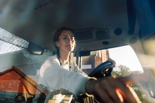 Female farmer starting ignition of tractor while working at farm