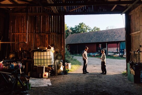 Male and female farm workers talking while standing at barn entrance