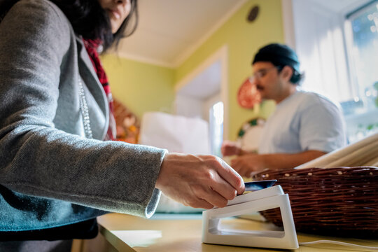 Woman paying via tap to pay method with credit card while shopping at home decor shop