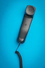 Vintage Black Telephone Handset on Vibrant Blue Background for Communication Concept