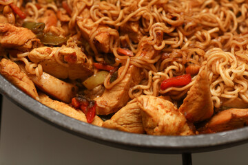 Noodles with meat and vegetables in a frying pan