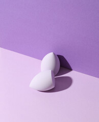 Makeup egg blenders on purple background. Beauty concept. Creative layout