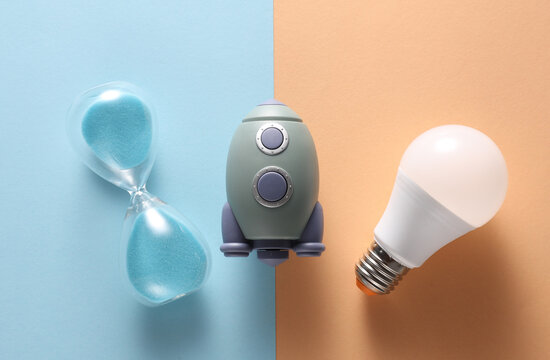 Toy space shuttle and hourglass, led light bulb on pink blue background. Startup, education, business concept - Powered by Adobe