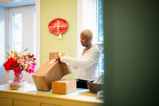 Female owner packing cardboard box standing at checkout in home decor shop