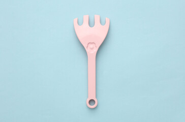 Children's plastic rake for sandbox on blue background