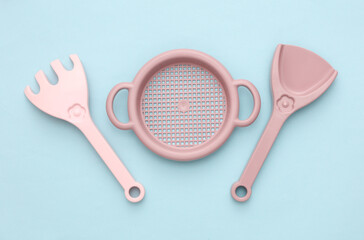 Children's sand sieve, rake and shovel on a blue background. Top view