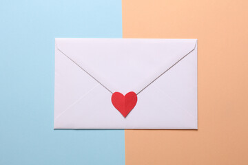 White envelope with paper heart on blue pink background. Love concept