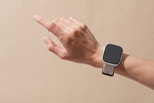 Female hand with modern smart watch on wrist, beige background - Powered by Adobe