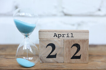 Wooden calendar cubes organizer with date april 22 and hourglass on wooden table
