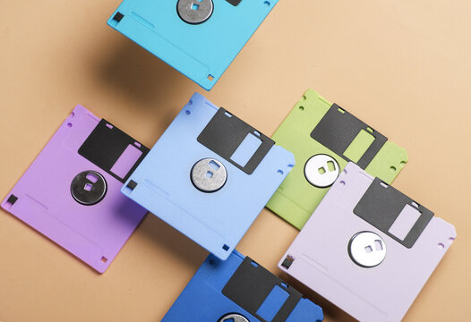 Floating colored retro 80s floppy disks on yellow background. Conceptual pop, creative layout