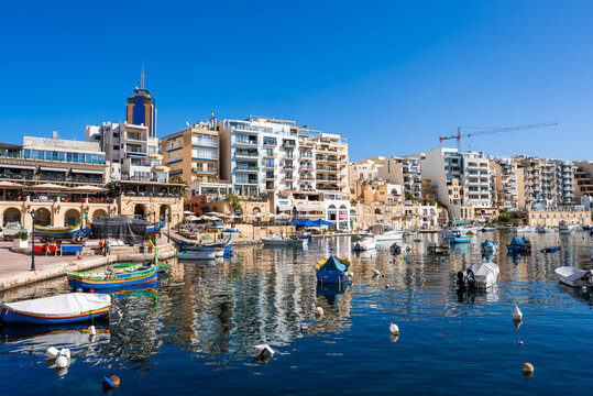 Spinola Bay Malta with luzzu boats and Portomaso Tower at noon