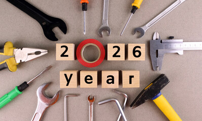 Year 2026 on gray background with various tools. Wooden cubes with numbers on a gray background