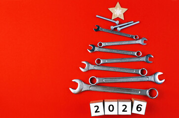 Christmas tree made of tools with wooden cubes "2026" on a red background