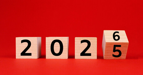Wooden cubes with numbers 2026 and 2025 on a red background. Symbol of the old 2025 and the new year 2026