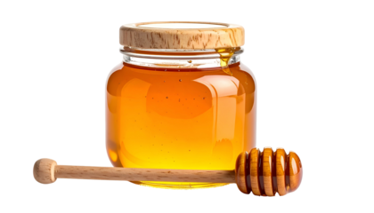 A clear glass jar of golden honey, a wooden dipper lies beside it, all on black