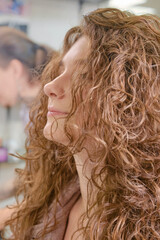 Close up of curlers in hair. Hands hairdresser doing a perm rolling the hair for a wavy effect or curly hair. Shallow depth of field