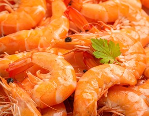 A close-up of cooked shrimp piled together, with a sprig of parsley as garnish