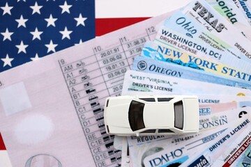 Toy car on big amount of driving licenses from different USA states on flag close up. Stack of driving license specimen cards