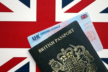 United Kingdom driving license with passport on UK flag close up