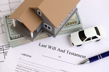 Generic toy house with US dollar bills, car and Last will and testament with pen on table close up