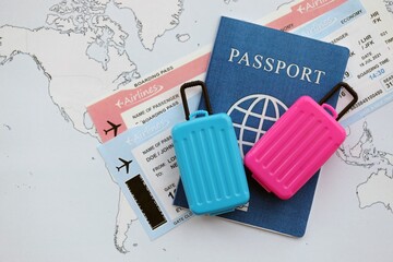 Passport with boarding pass tickets and toy luggage bag on world map close up