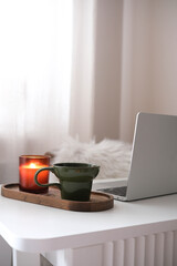  Homeoffice with Christmas decoration - Notebook, green glass with coffee, candle on white table.