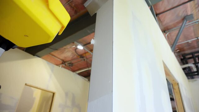 construction worker applies joint compound to drywall end using a metal spatulas. Worker smoothing seams and preparing the surface for finishing