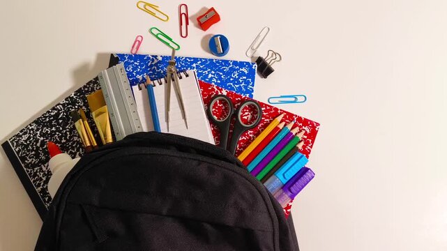 Back to school supplies with scissor, books, markers, colored pencil crayons, gel pens, ruler, sharpener, compass, calculator, notepad, paper clips in a backpack education, student, children, learning