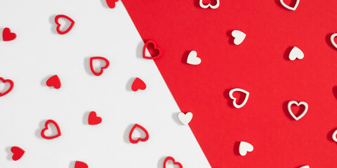 Valentine’s Day background with red and white wooden hearts on divided red and white paper. Minimal flat lay composition for love, romance, and holiday greeting card design with copy space