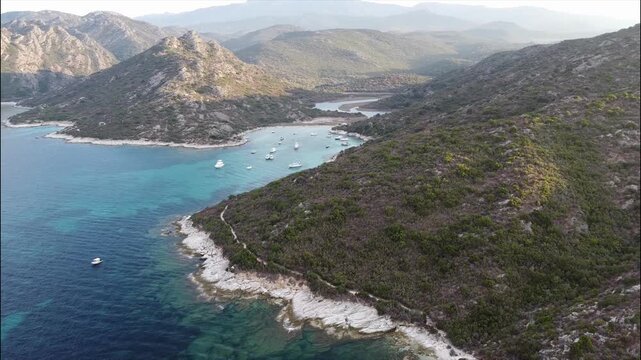 Aerial view of Plage de Fiume Santu beach, Corsica, France. Turquoise waters and boats anchored in a scenic wild bay surrounded by rocky hills.