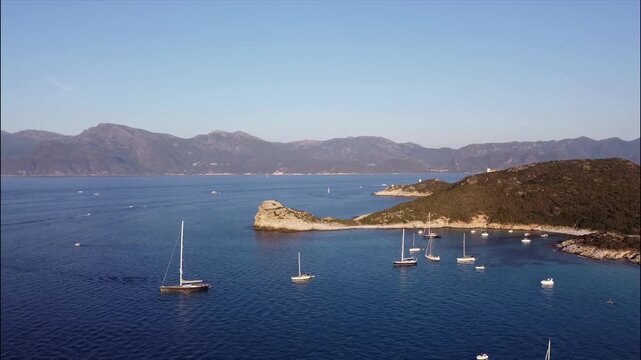 Aerial view of Punta Cavallata, Cap Corse, Corsica, France. Sailboats anchored in a turquoise Mediterranean bay surrounded by rugged coastal hills