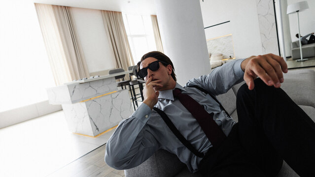 A successful and confident young businessman smokes in his ideal apartment while sitting on the couch