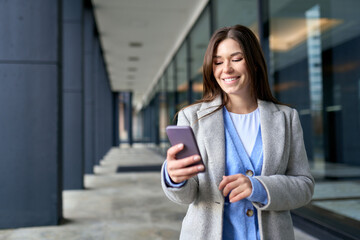 Young smiling happy woman, busy business lady standing outside office building on city street...