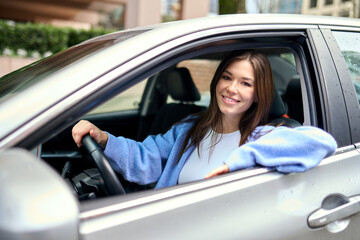 Portrait of young happy woman customer driver sitting inside car looking at camera. Driving school...