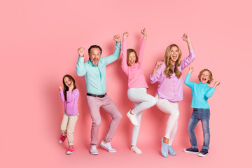 Family celebration in a pink studio with parents and kids jumping and smiling together in bright pastel outfits